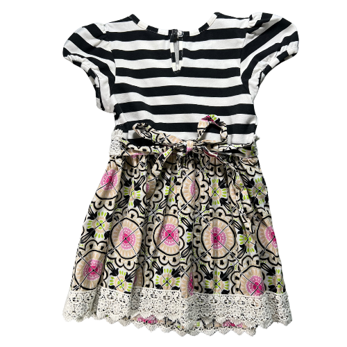 Pre-owned Counting Daisies dress in black, white, and pink with a floral pattern, paired with black and white striped leggings. The dress features cap sleeves, a lace trim, a fabric floral accent, and an attached tie belt. The leggings have an elastic waistband and ruffled hems. Size 6, gently used condition. Shop www.ourfamiliesatticcom