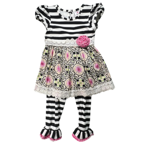 Pre-owned Counting Daisies dress in black, white, and pink with a floral pattern, paired with black and white striped leggings. The dress features cap sleeves, a lace trim, a fabric floral accent, and an attached tie belt. The leggings have an elastic waistband and ruffled hems. Size 6, gently used condition. Shop www.ourfamiliesatticcom