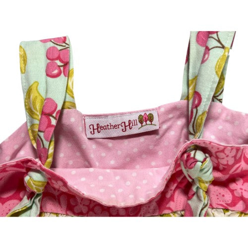 Pre-Owned Pink and White Polka Dot Dress Brand: Heather Hill Size: Little Girl 6 (an estimate on size) Color: Pink, white, and green with polka dots, cherries, apple, and floral print. Features: Sleeveless, 1.5" shoulder strap, cute knot on the straps, small apron, wide hem Material: Cotton Condition: Good, Gently used. There is a small mark on the back at the hem. Used clothing. Our Families Attic