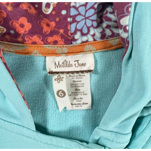 Pre-Owned Hooded Jacket Brand: Matilda Jane Size: Little girl size 6 Color: Turquois with shades of purple and orange florals Features: Long sleeves, zip-up, lined hood, ruffles, soft material, decorative patch on sleeve Material: 95% Cotton, 5% Spandex Condition: Gently used, good condition. Minor sains at the end of cuffs and sleeve. Online thrift store - Our Families Attic