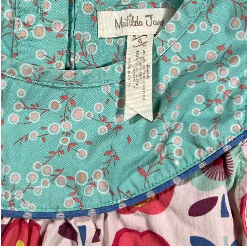 Pre-owned Matilda Jane Lucia Shabby Apple Top for little girls, size 6, featuring a light multicolor design with apple and floral prints, cap ruffle sleeves, button closure at the back, and ribbon trim, available at Our Families Attic.