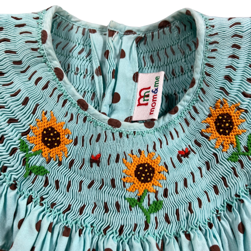 Pre-owned Mom & Me Aqua Smocked Dress with Brown Polka Dots for little girls, size 6X, featuring rickrack trim on the shoulder ruffle, sunflower embroidery, and a 4-button closure, available at Our Families Attic.