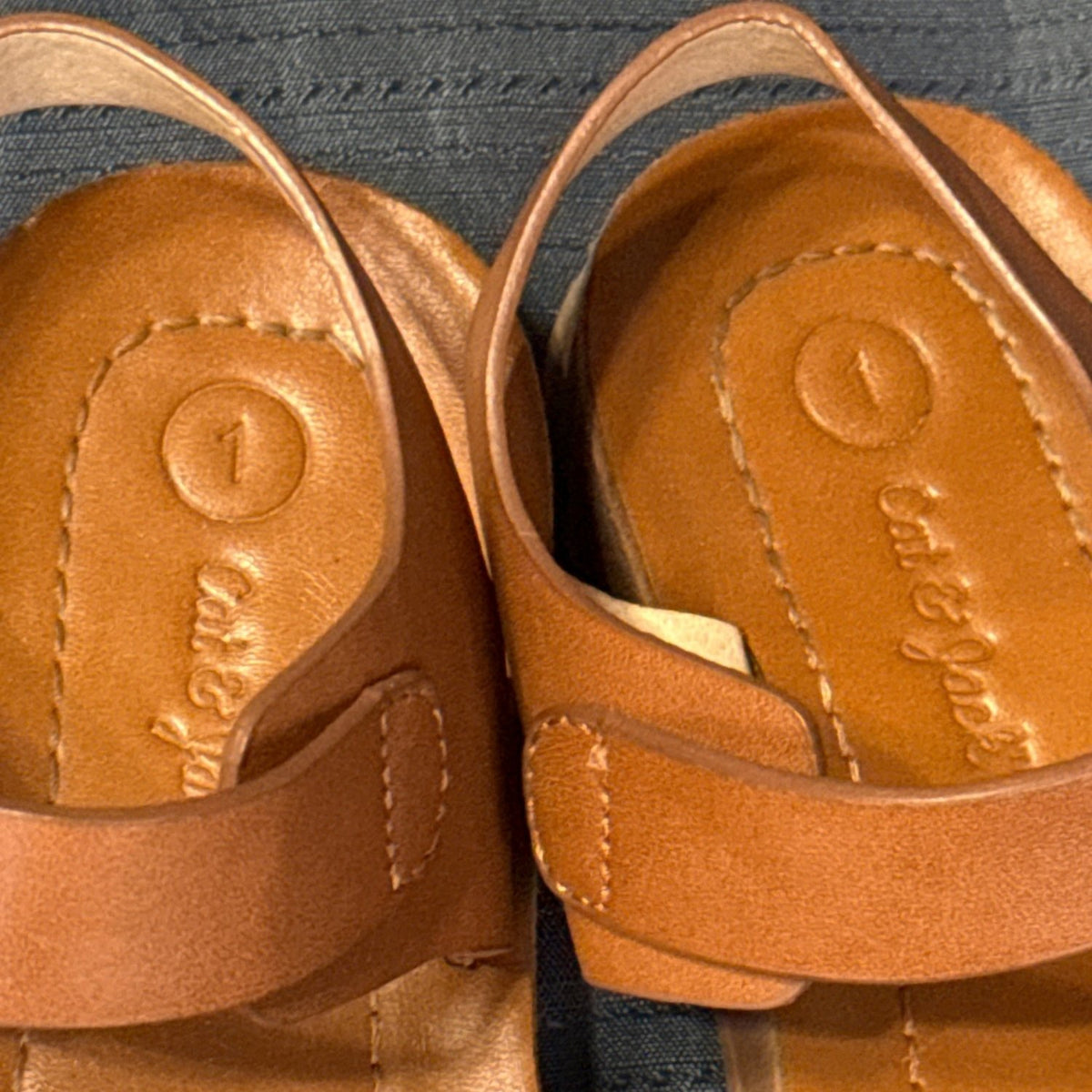 Close-up of Cat & Jack girls’ tan-brown sandals showing surface details and wear.