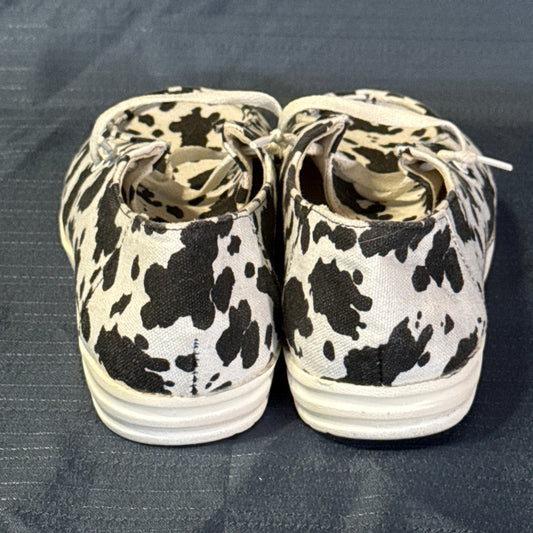 Back view of cow-print canvas shoes showing heel seams and light-colored soles.