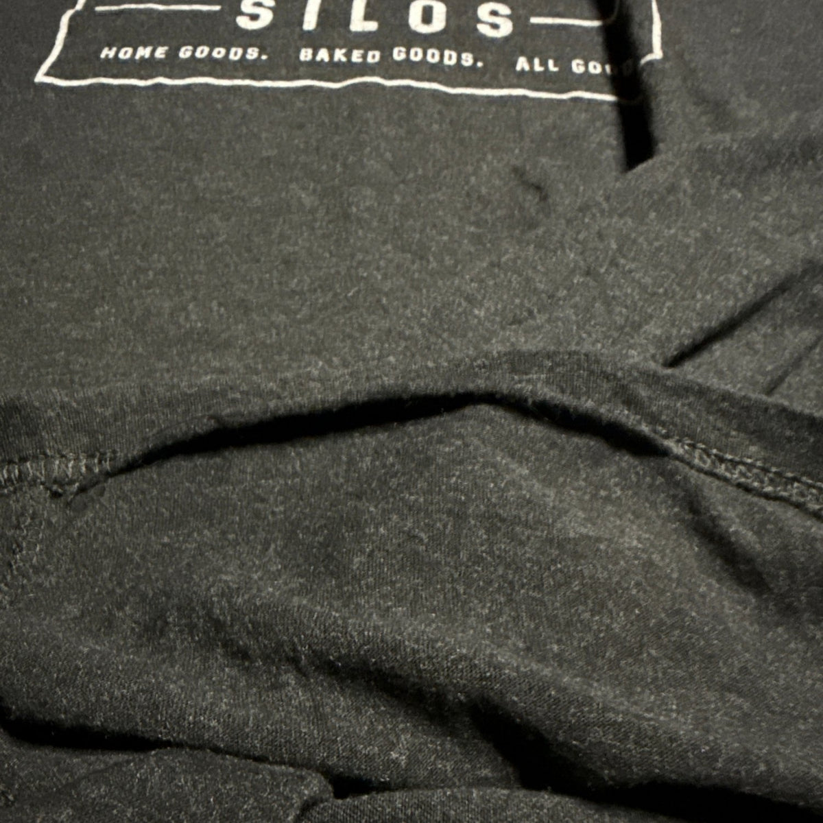 Close-up of loose stitching at another section of the T-shirt’s bottom hem.