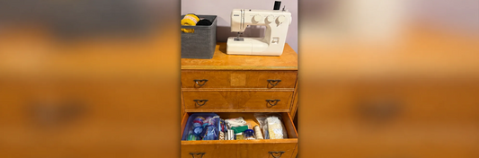 Papa’s vintage wooden dresser repurposed for craft storage, topped with a Kenmore sewing machine and yarn basket, with an open drawer of sewing supplies.