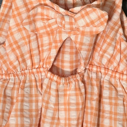 Close-up of oversized gingham bow and back keyhole opening on Carter's orange and white baby romper.
