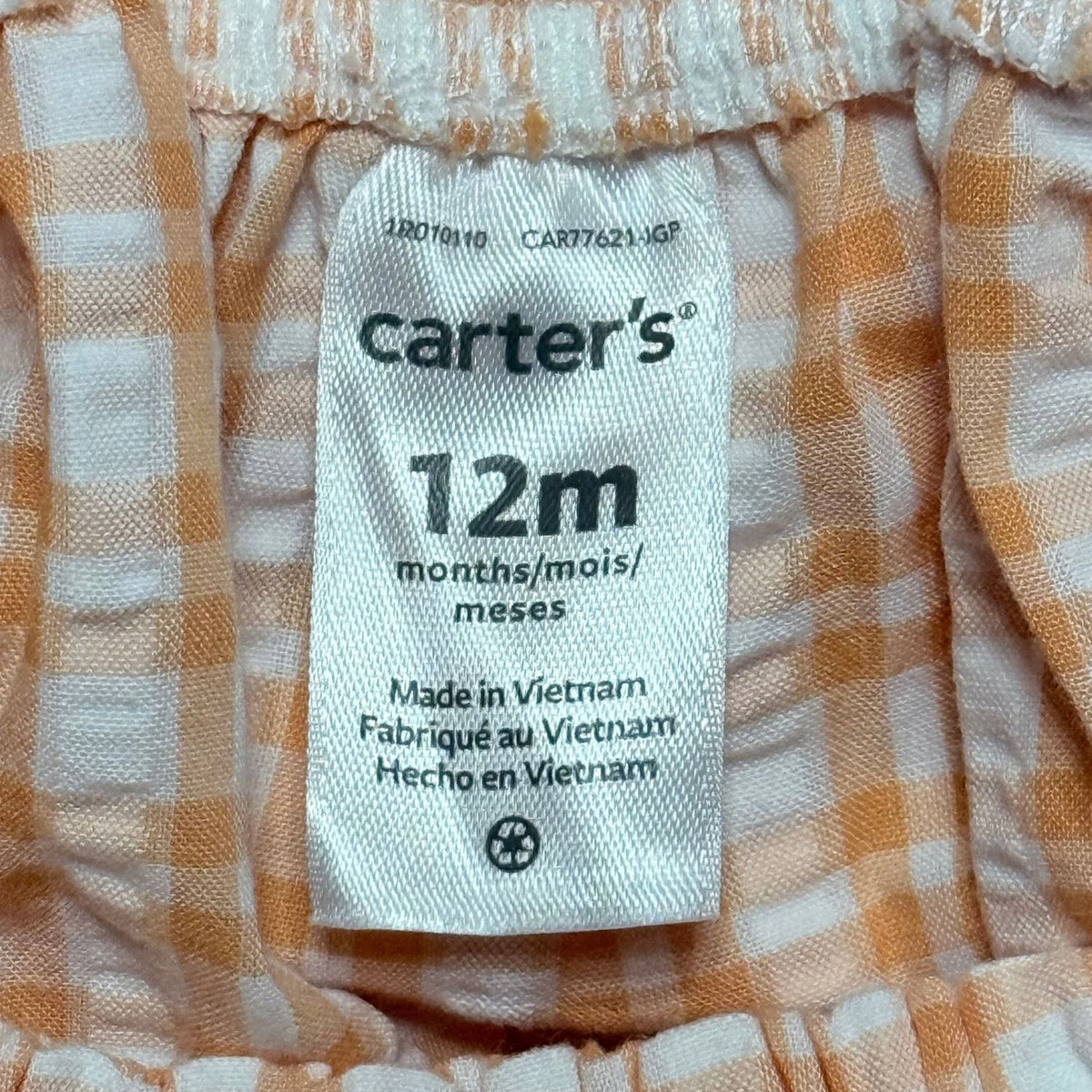 Carter's baby girls clothing label showing size 12 months inside orange and white gingham romper.