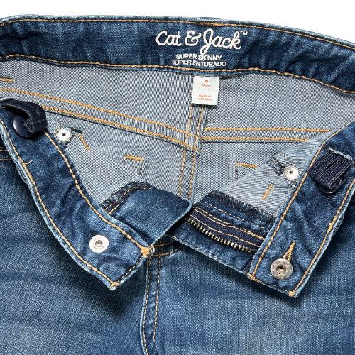 Pre-owned Cat & Jack super skinny jeans for little girls in size 6. Medium wash denim with adjustable waist, two back pockets, faux front pockets, and zipper and snap closure with a faux button. Made from a blend of cotton, recycled polyester, lyocell, and rayon. Gently used condition. Shop at www.ourfamiliesattic.com