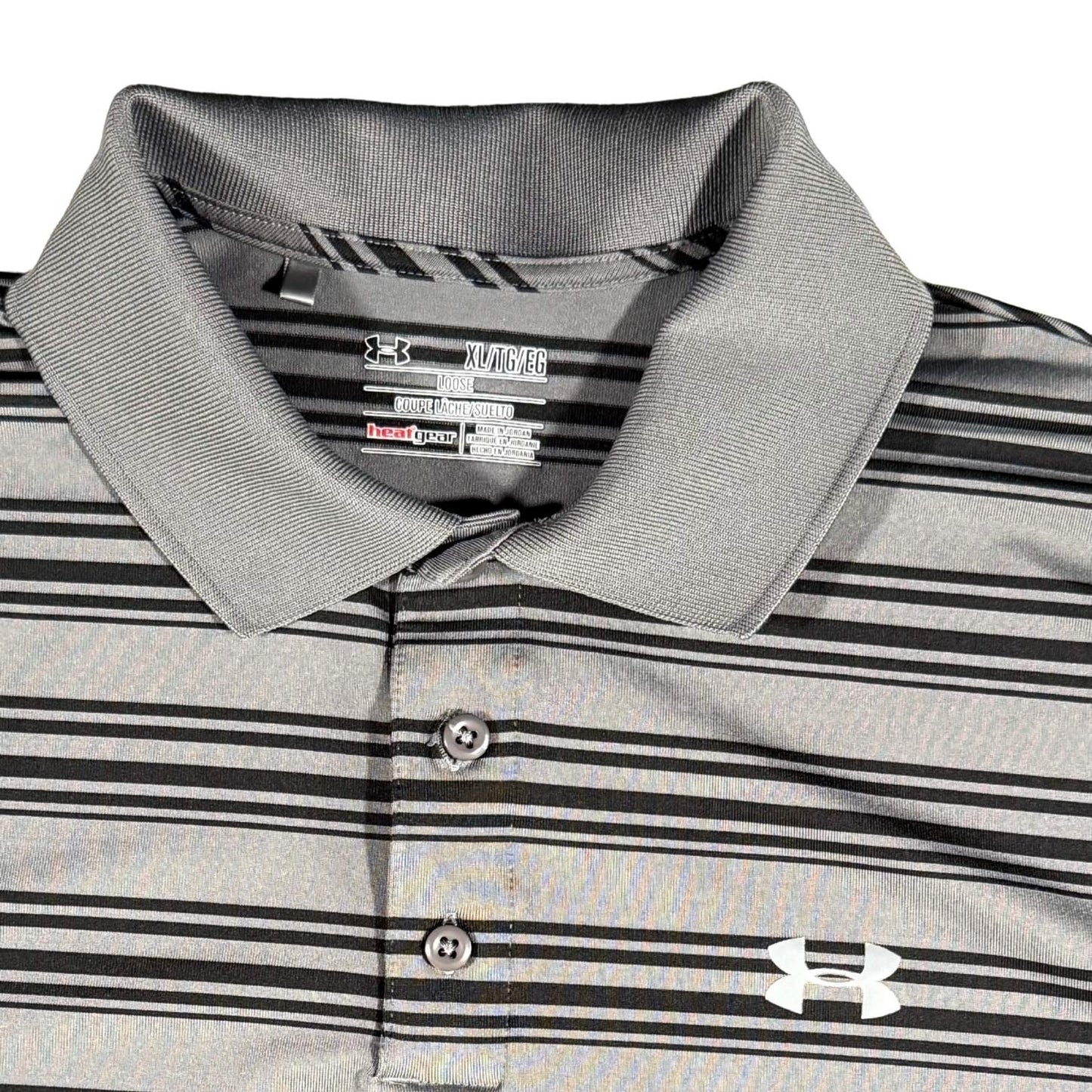 Close-up of the embroidered Under Armour logo and collar on a gray striped HeatGear performance polo.