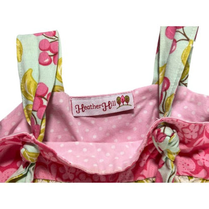 Pre-Owned Pink and White Polka Dot Dress Brand: Heather Hill Size: Little Girl 6 (an estimate on size) Color: Pink, white, and green with polka dots, cherries, apple, and floral print. Features: Sleeveless, 1.5" shoulder strap, cute knot on the straps, small apron, wide hem Material:  Cotton Condition:  Good,  Gently used. There is a small mark on the back at the hem. Used clothing. Our Families Attic