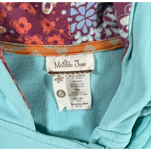 Pre-Owned Hooded Jacket Brand: Matilda Jane Size: Little girl size 6 Color: Turquois with shades of purple and orange florals Features: Long sleeves, zip-up, lined hood, ruffles, soft material, decorative patch on sleeve Material:  95% Cotton, 5% Spandex Condition:  Gently used, good condition. Minor sains at the end of cuffs and sleeve. Online thrift store - Our Families Attic