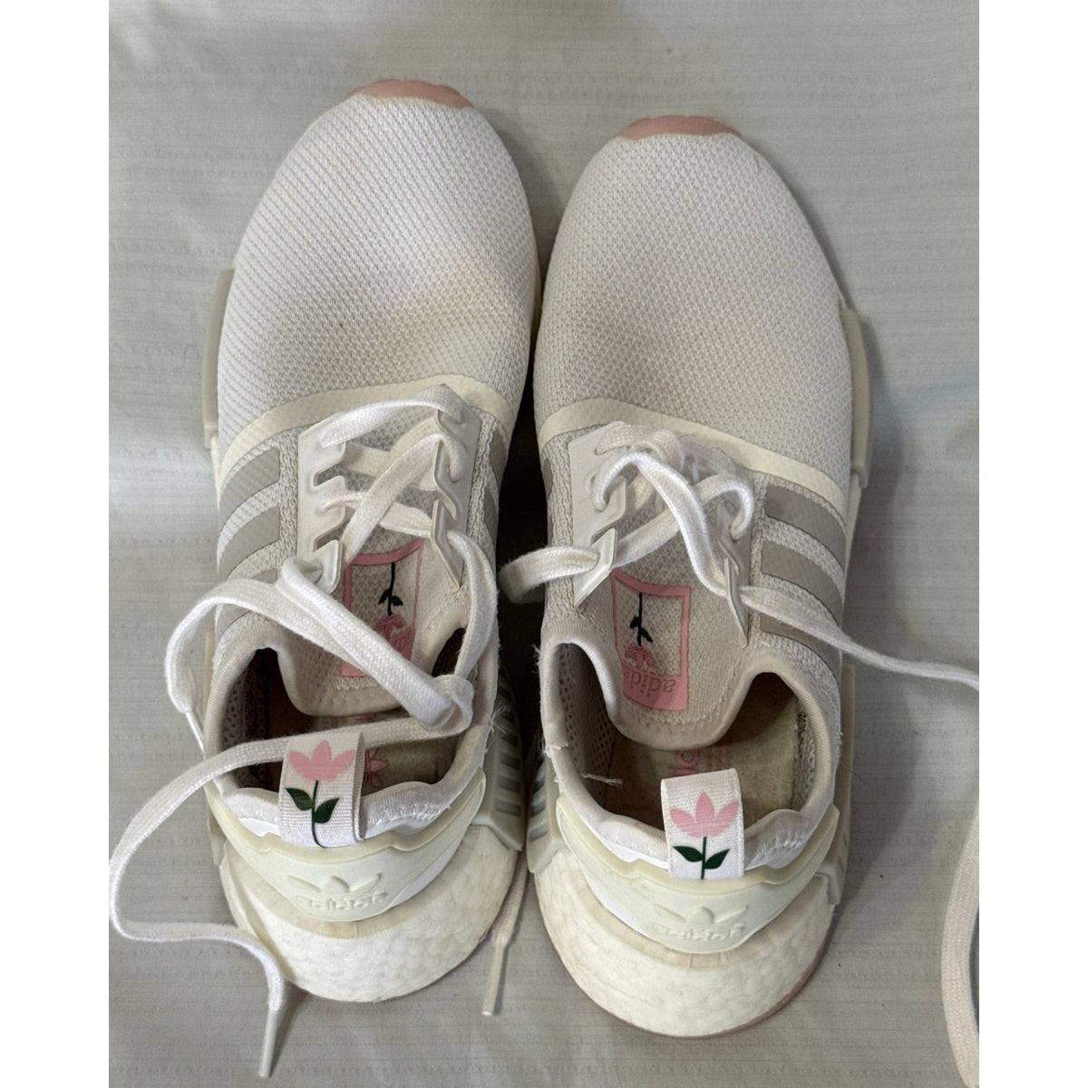 Rear and top view of Adidas sneakers showing heel tabs with pink flowers and green stems.