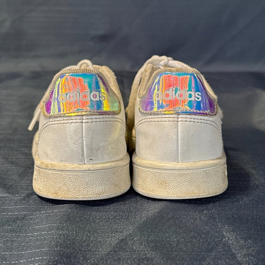 Back view of white Adidas sneakers showing iridescent logo heel tabs and scuffs.
