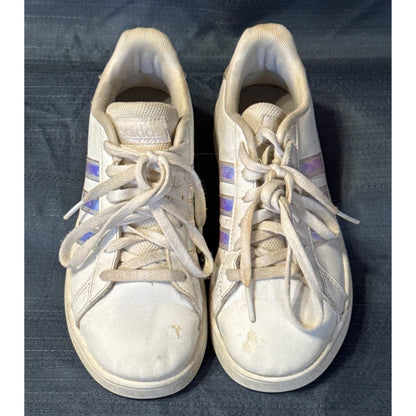 Front view of white Adidas sneakers showing laces, rounded toes, and visible dirt and marks.