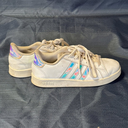 Side view of white Adidas low-top sneakers with iridescent three-stripe accents and heel tabs.
