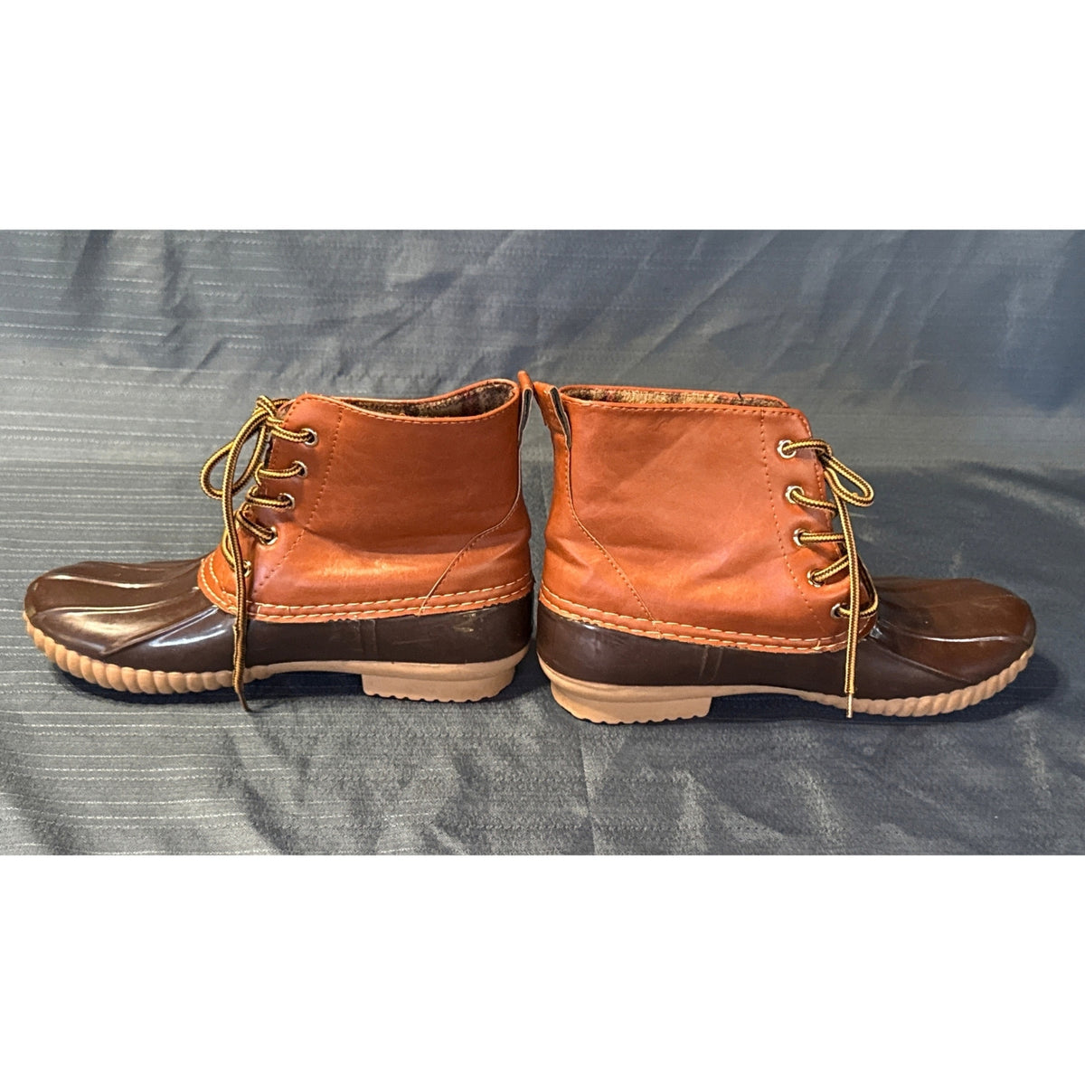 Side profiles of brown ANNA lace-up duck boots with dark brown rubber bottoms and tan soles.