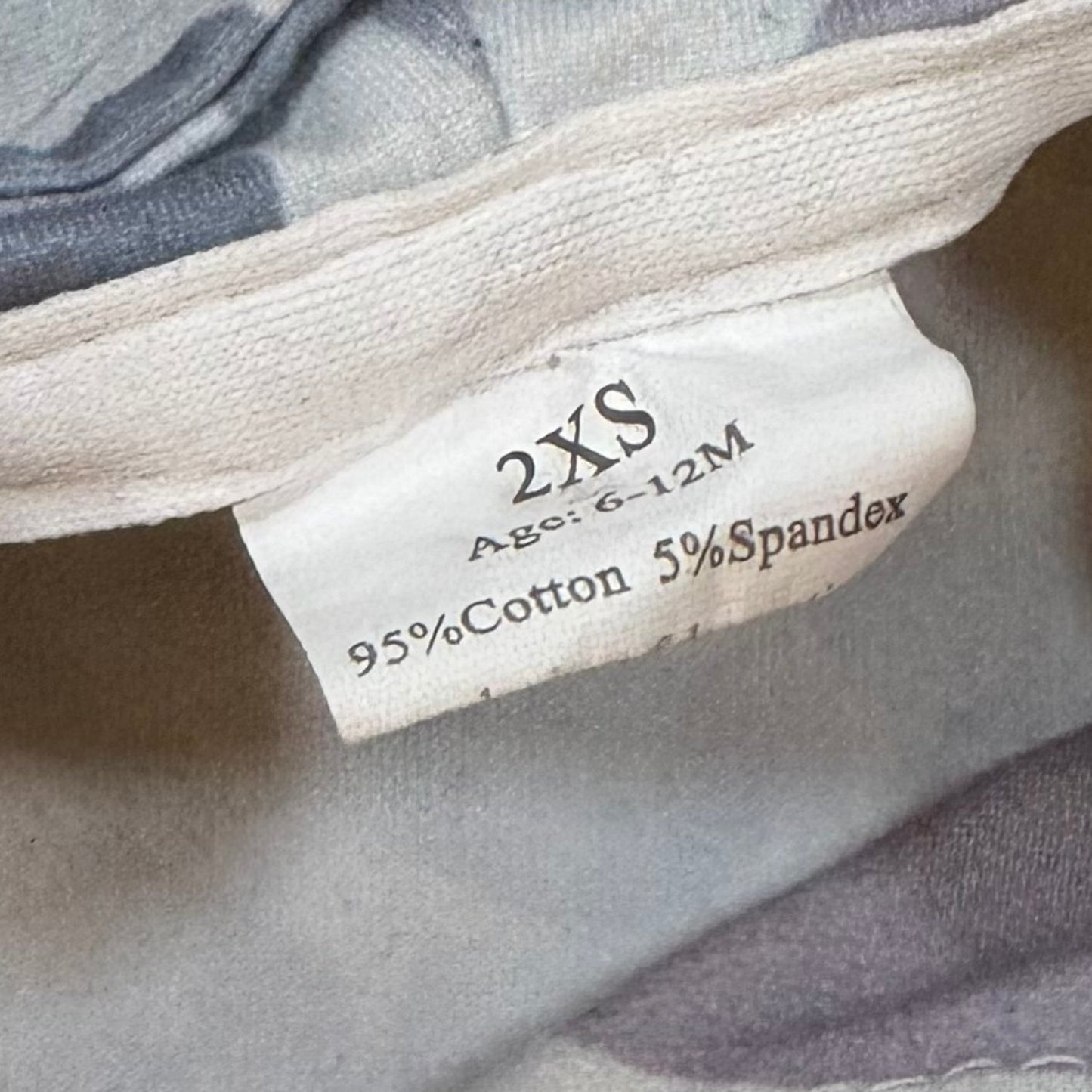 Size and material tag on baby boy gray camo set showing 6-12 months