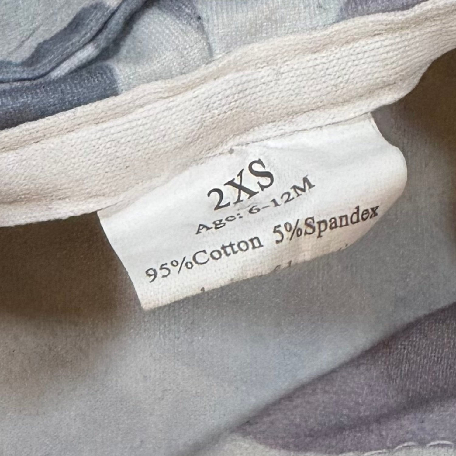 Size and material tag on baby boy gray camo set showing 6-12 months