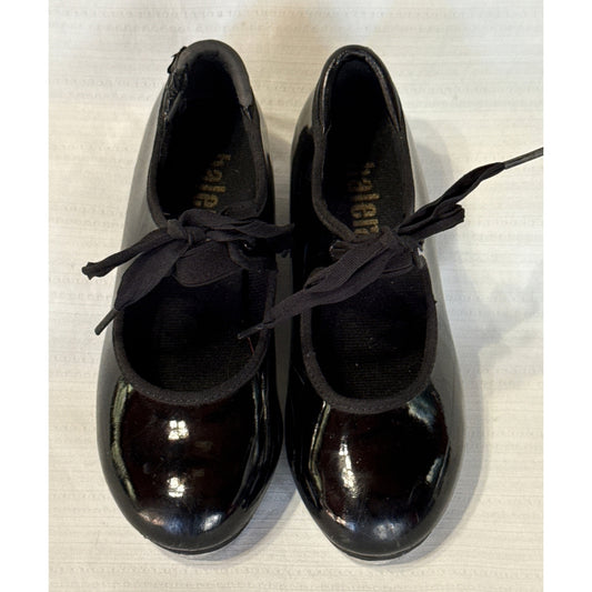 Front view of glossy black Balera tap shoes showing rounded toes and black bow ties.