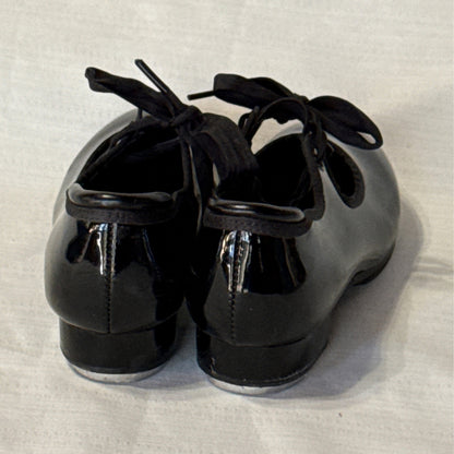 Back view of Balera black tap shoes showing heel seams, glossy uppers, and low block heels.
