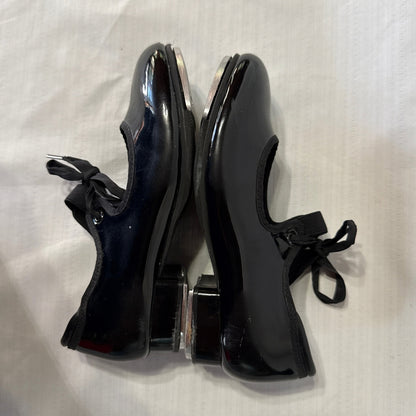 Outer side view of Balera black tap shoes showing scratches and scuffs on the glossy uppers.
