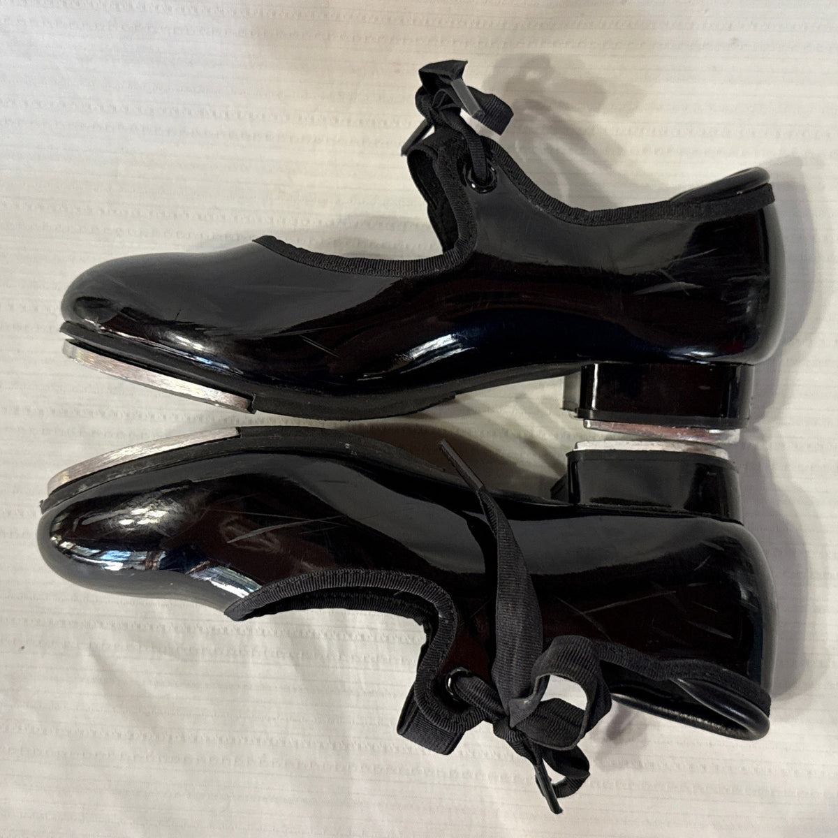 Inner side view of Balera black tie tap shoes showing low heels and metal tap edges.

