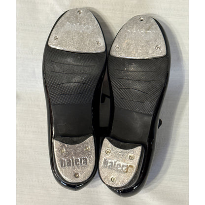 Soles of Balera black tap shoes showing worn metal toe and heel taps, with one screw missing from the left toe tap.
