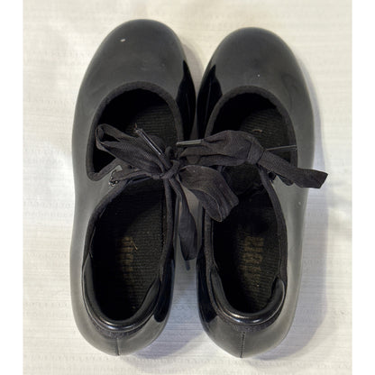 Top view of Balera black tap shoes showing bow ties, shoe openings, and worn insole branding.
