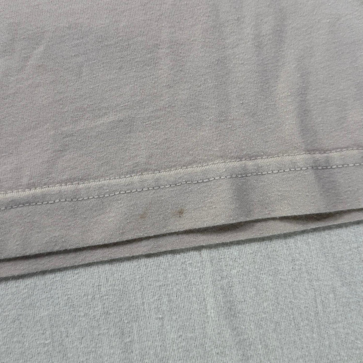 Small stains on front bottom hem of beige t-shirt