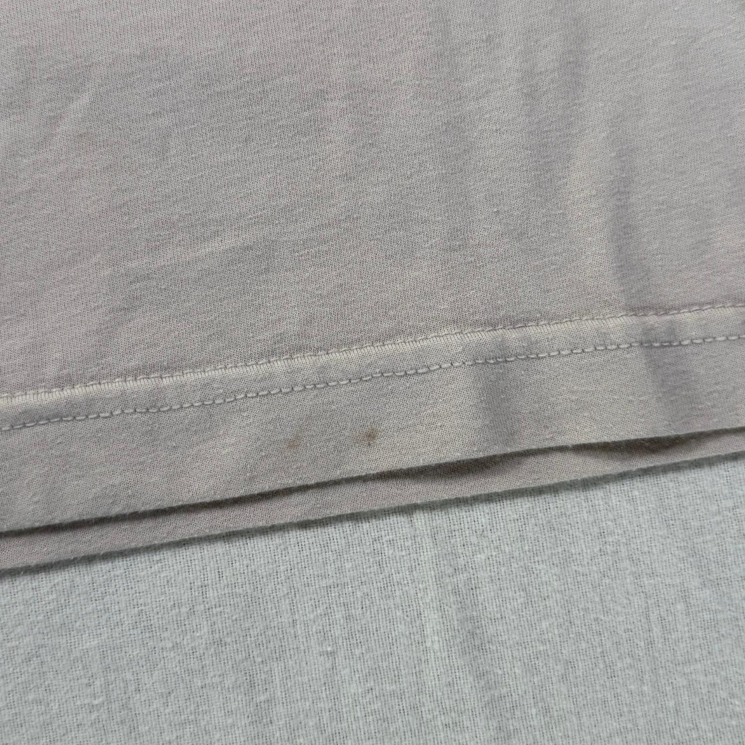 Small stains on front bottom hem of beige t-shirt