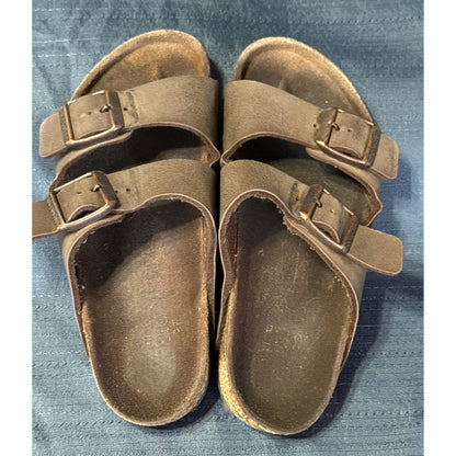 Top view of brown Birkenstock sandals showing two adjustable buckle straps and darkened footbeds.
