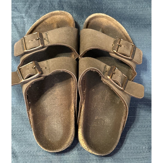Top view of brown Birkenstock sandals showing two adjustable buckle straps and darkened footbeds.
