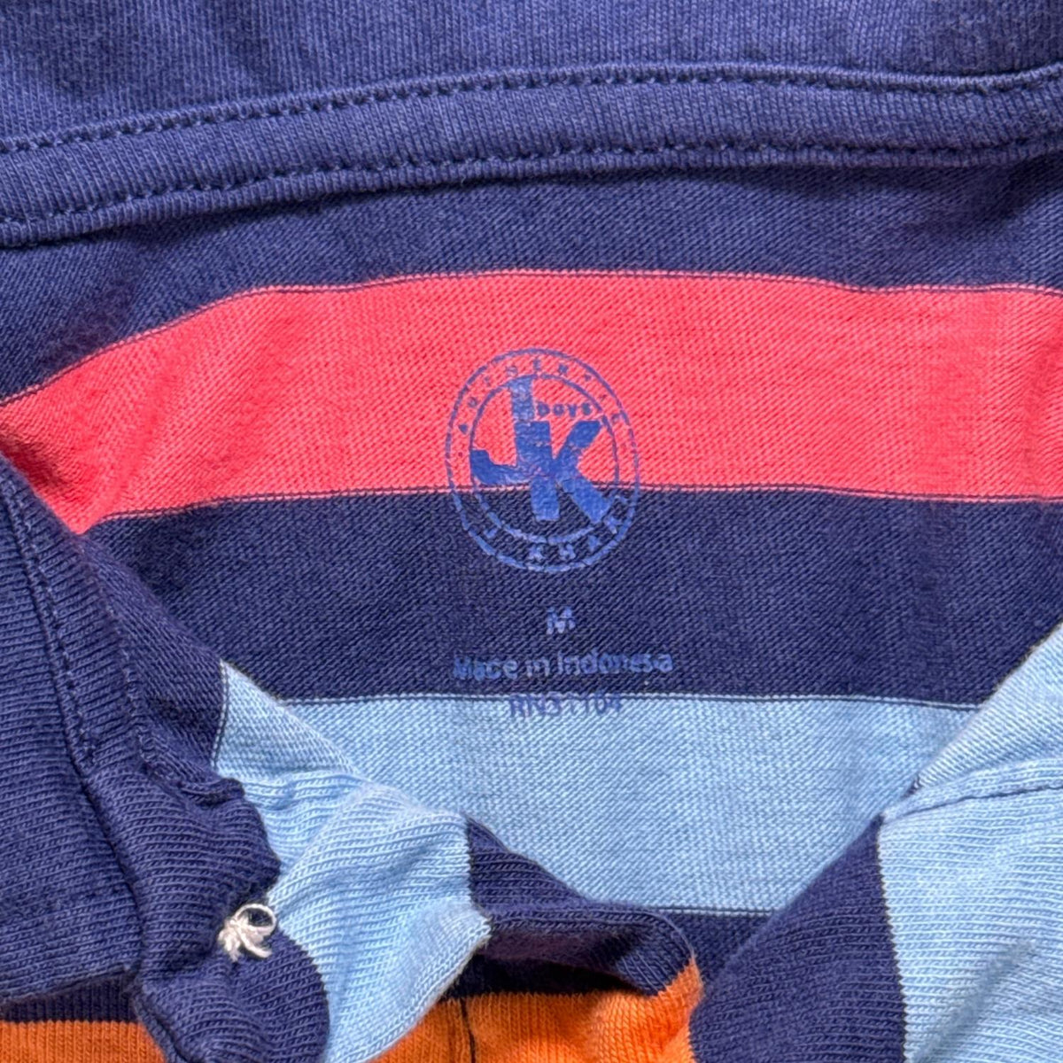 Close-up of the J. Khaki brand and Medium size marking inside the boys’ striped polo.
