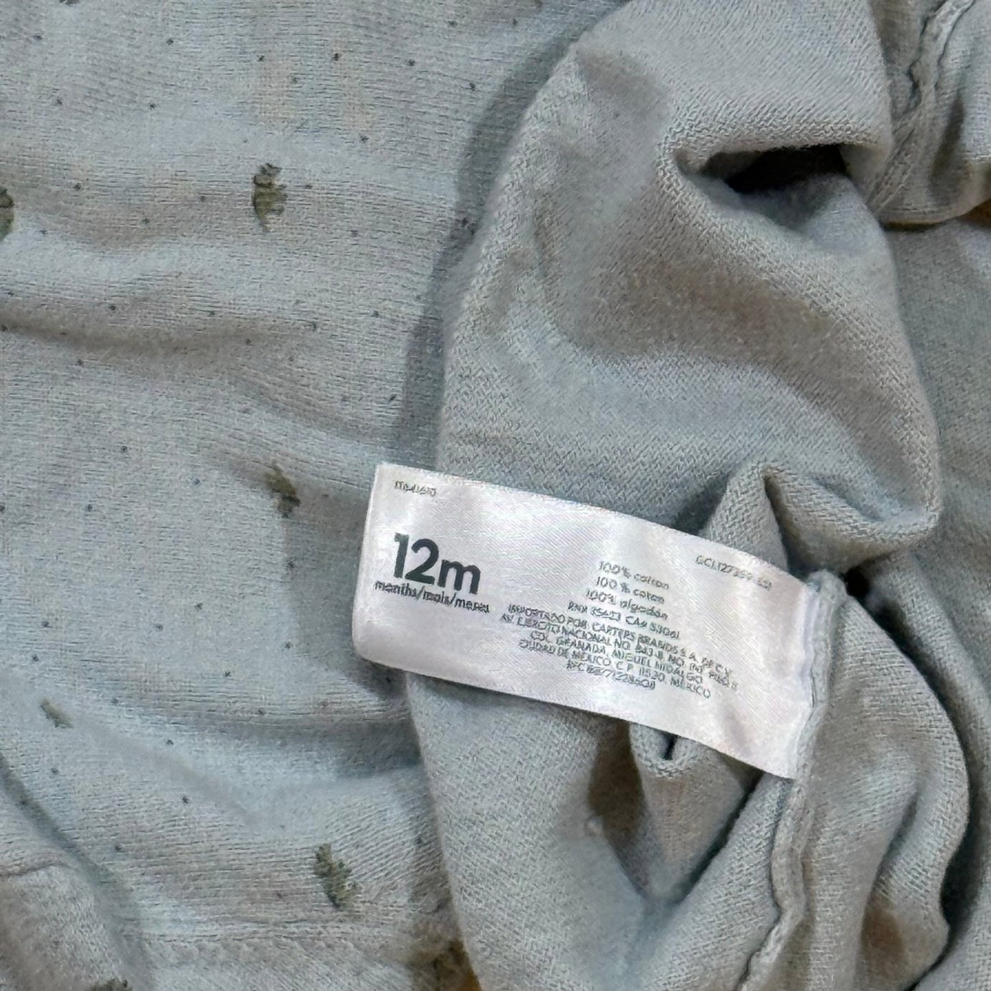 Carter's 12 month dinosaur sweater care and material tag showing 100% cotton
