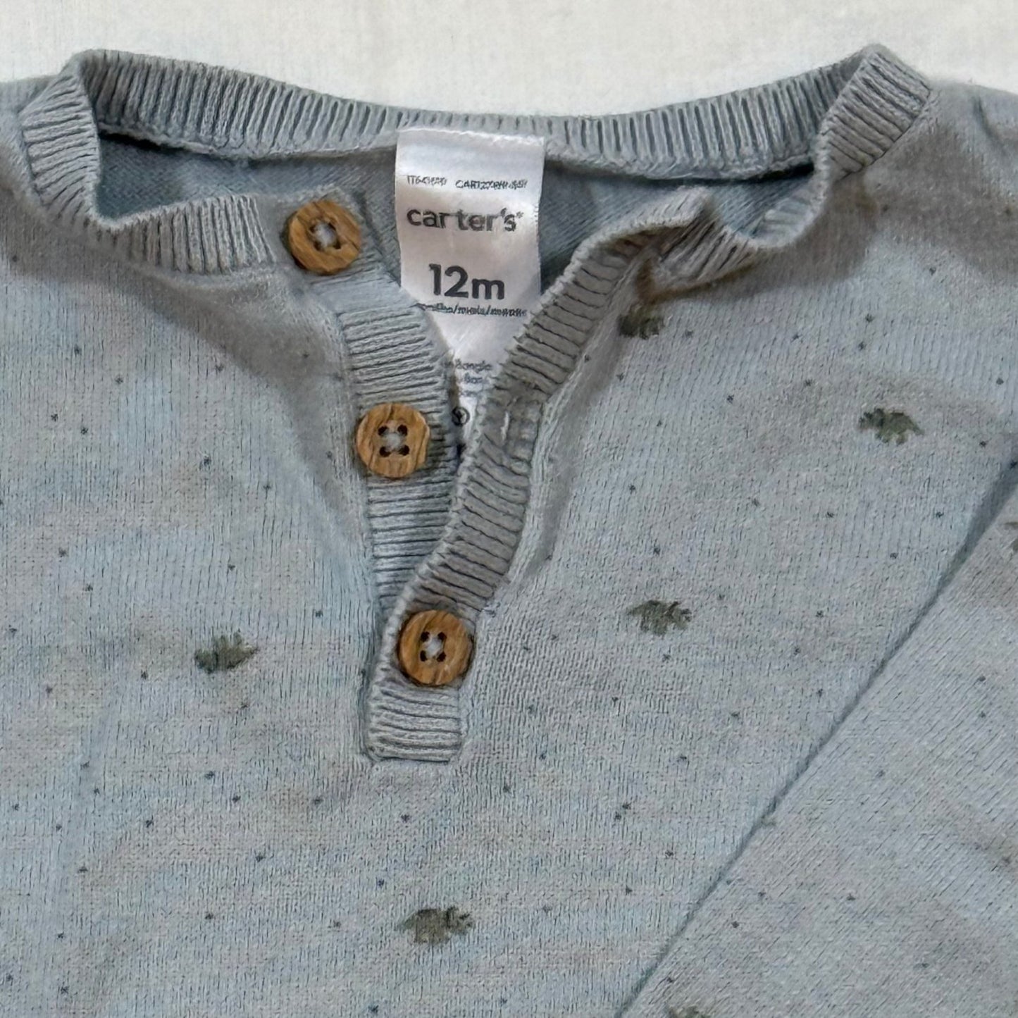 Close-up of Carter's 12 month dinosaur sweater Henley neckline with three wood-look buttons and size tag