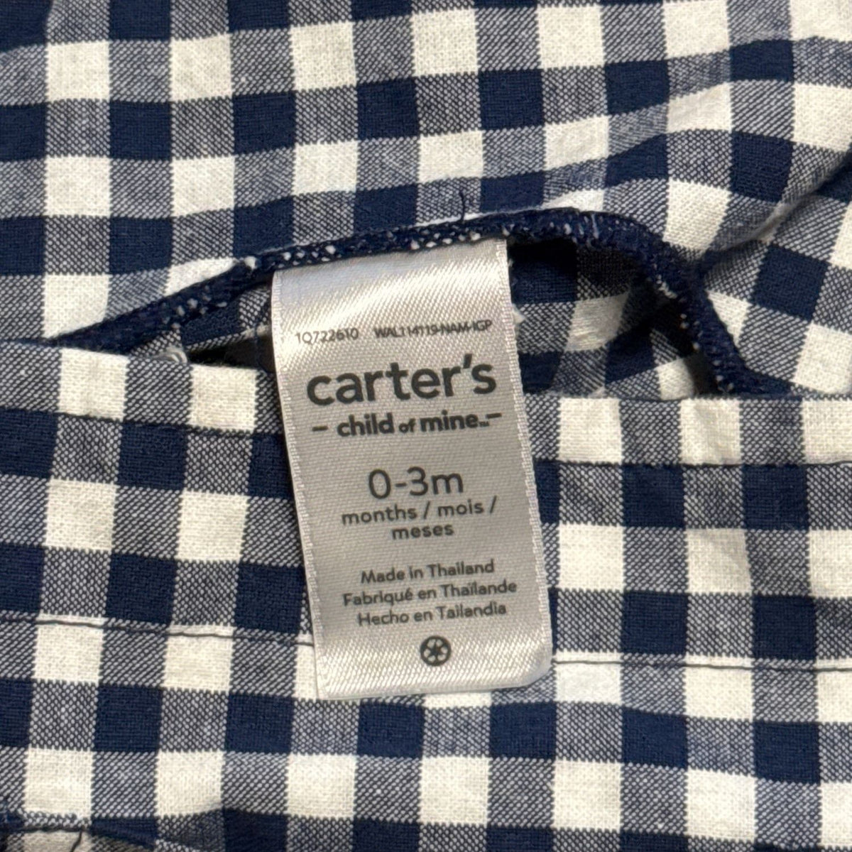 Carter's Child of Mine clothing label showing baby size 0–3 months inside navy blue and white gingham dress.