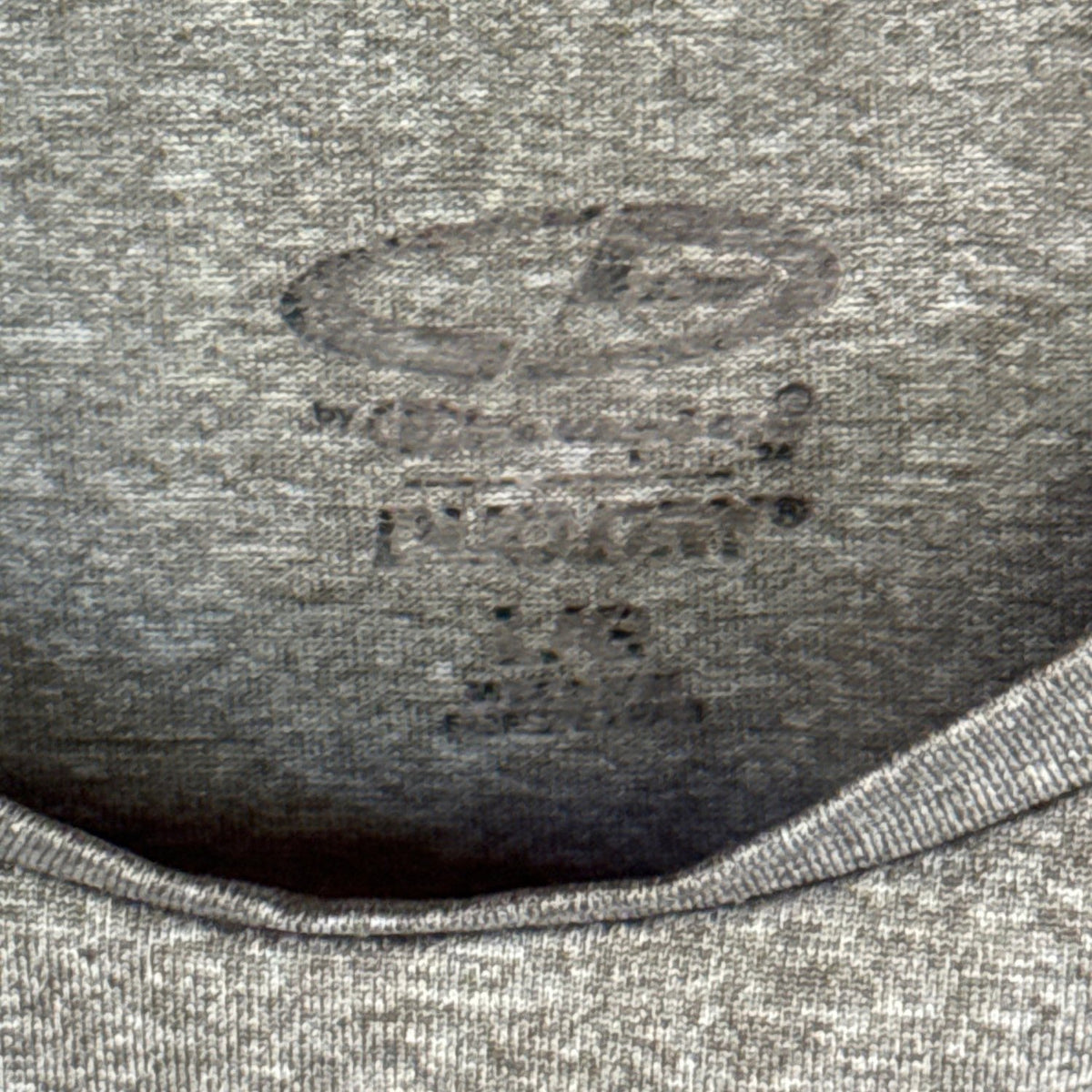Close-up of the worn printed Champion Duo Dry neckline label on a heather gray shirt.