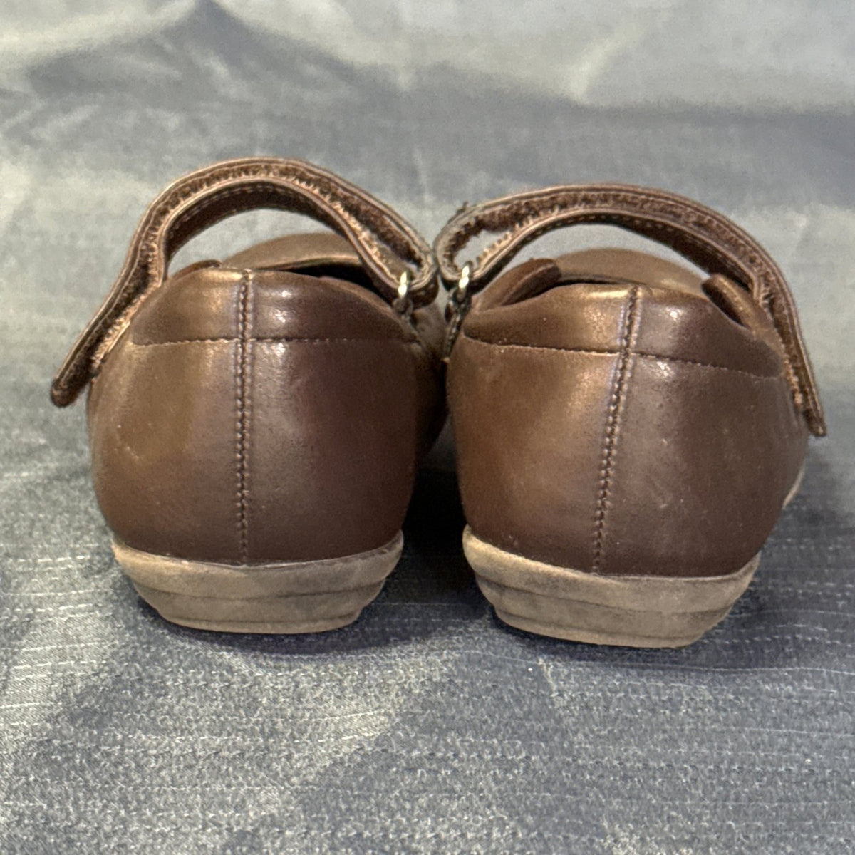 Back view of brown Mary Jane shoes showing heel seams and surface wear.