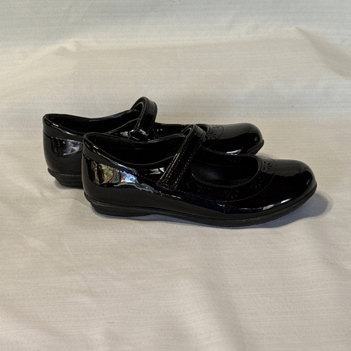 Right side view of The Children’s Place black Mary Jane shoes showing glossy uppers, instep straps, and low heels.
