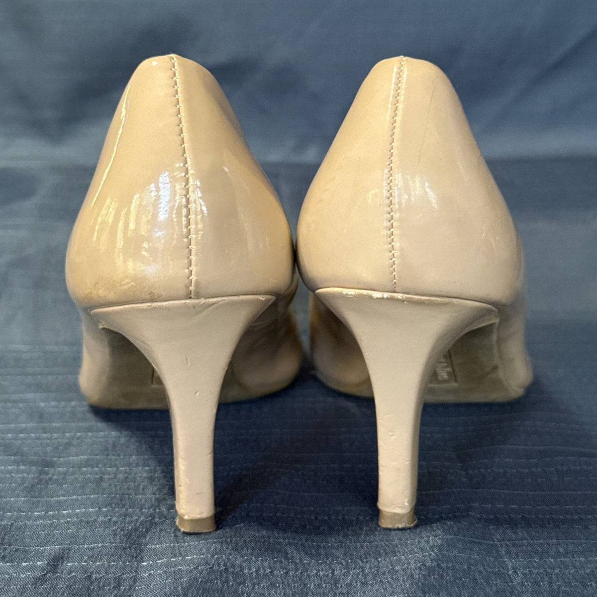 Back view of nude beige pumps showing heel seams and scuffs on the tapered heels.
