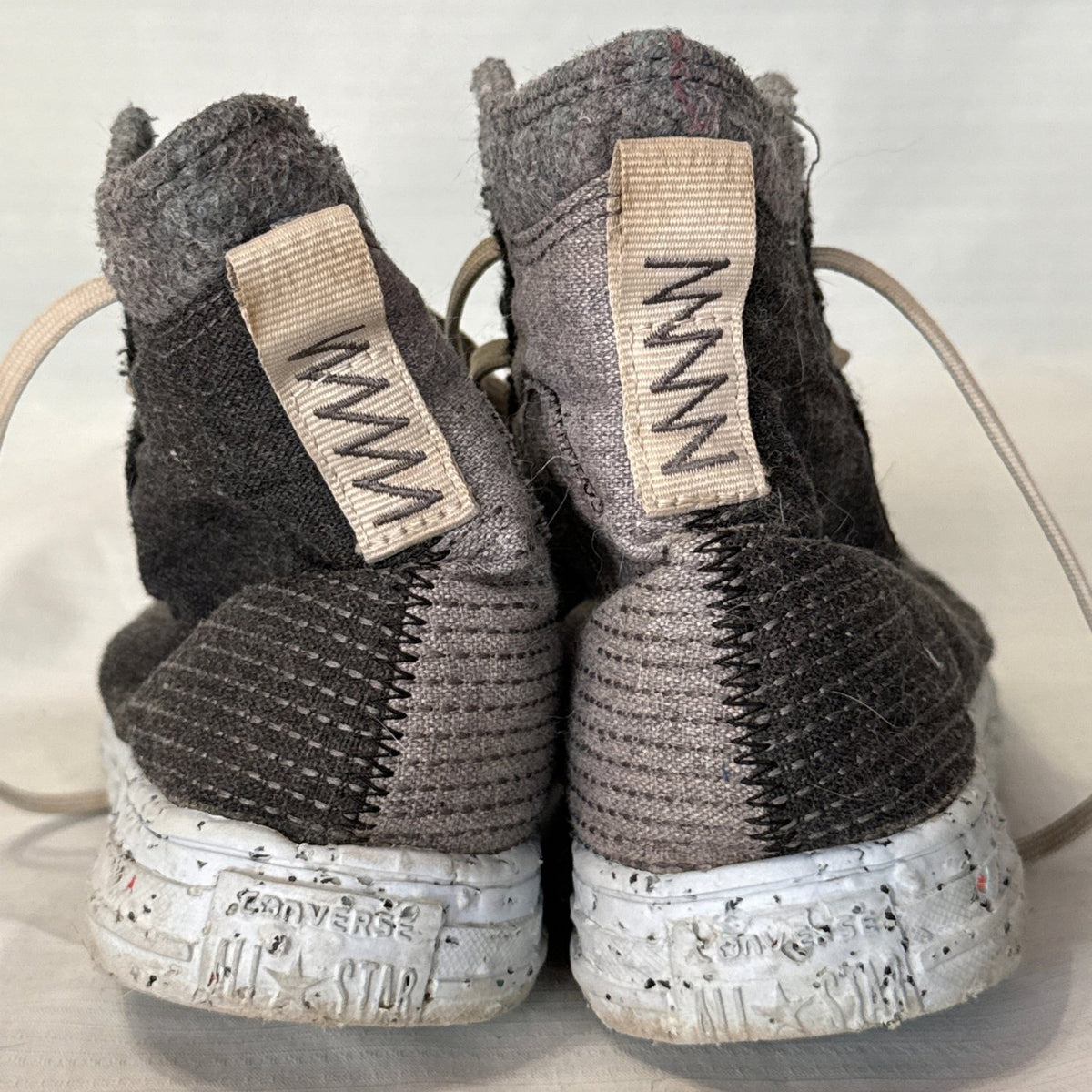 Back view of Converse Crater high-top sneakers showing gray and black textured fabric, heel pull tabs, and speckled soles.