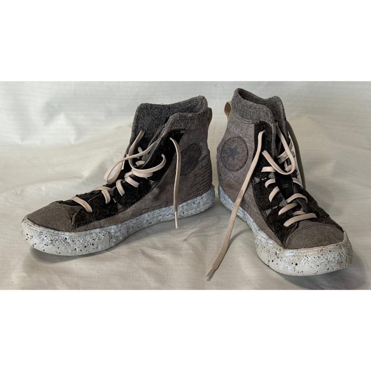 Angled view of Converse Chuck Taylor All Star Crater gray and black high-top sneakers with speckled soles and ankle patches.