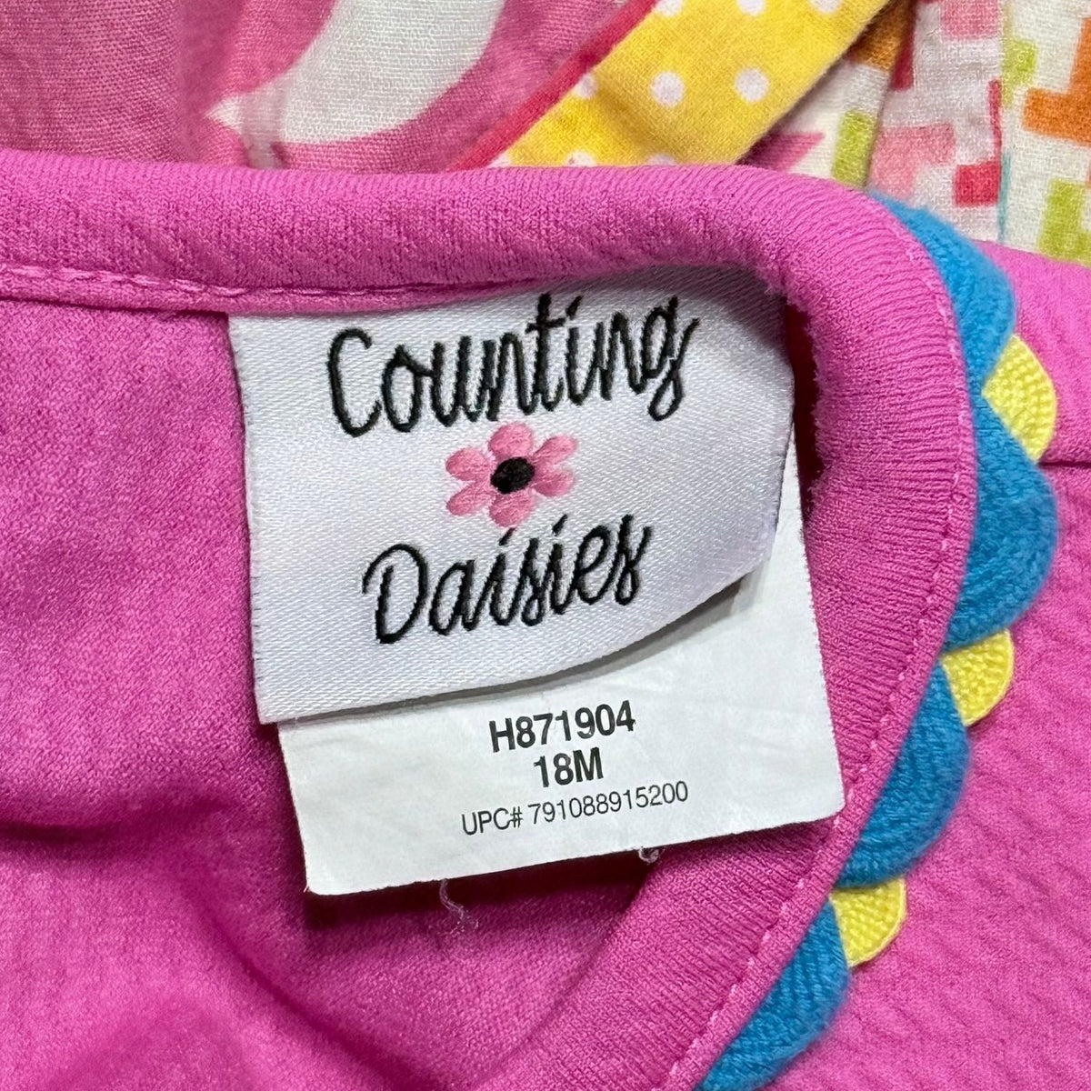 Counting Daisies brand label showing size 18 months on pink baby girls dress.
