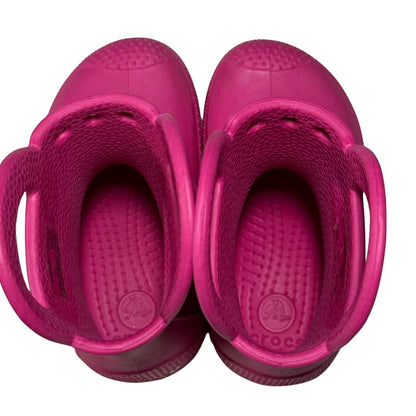 Angled view of pink Crocs toddler rain boots.
