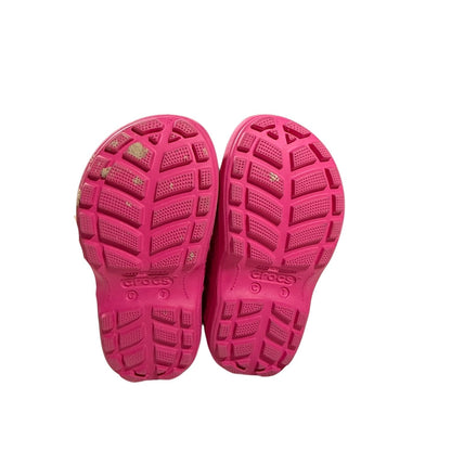 Outsoles of pink Crocs toddler rain boots showing tread.