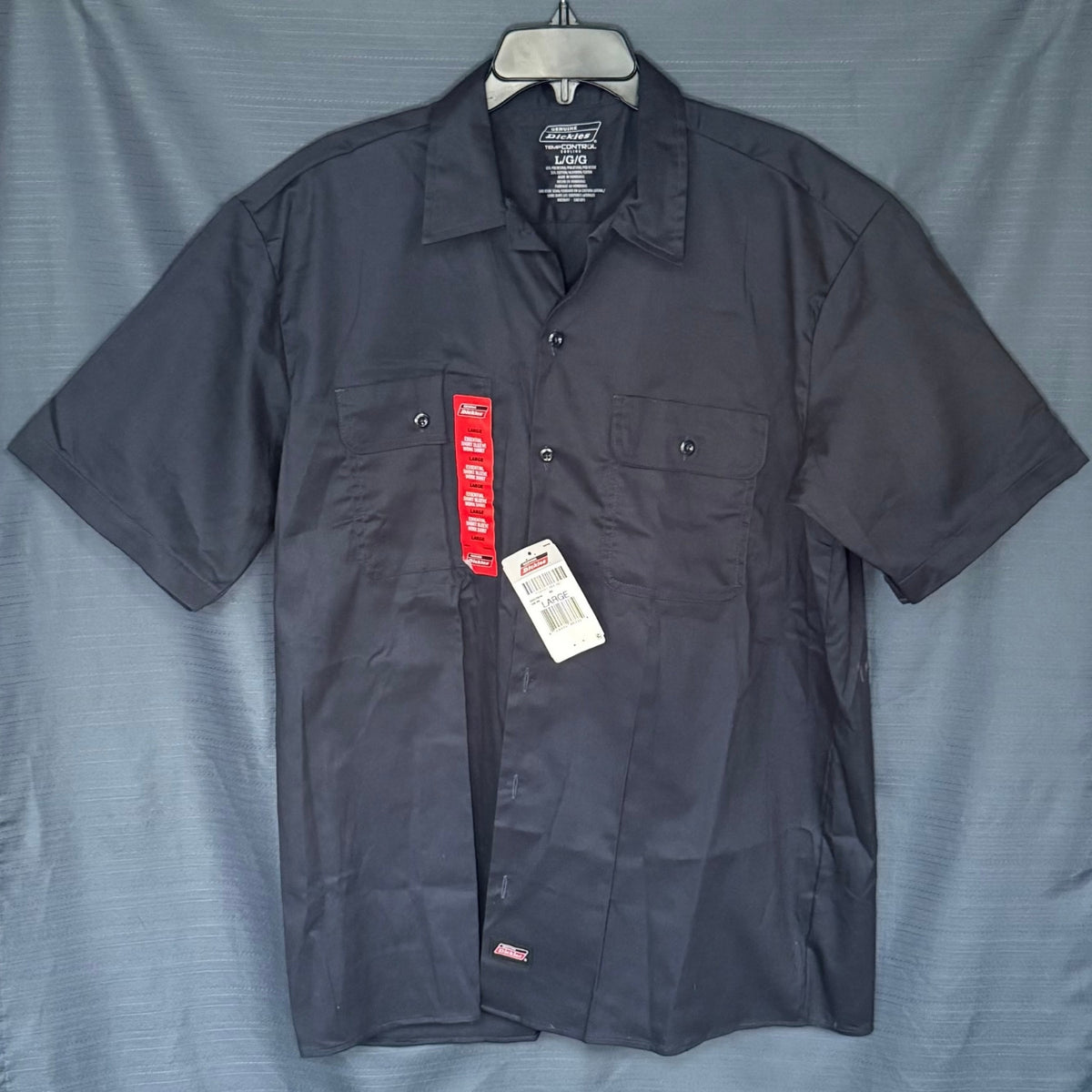 Front view of new Dickies men's large navy short sleeve button-up work shirt with two button-flap chest pockets and original tags.