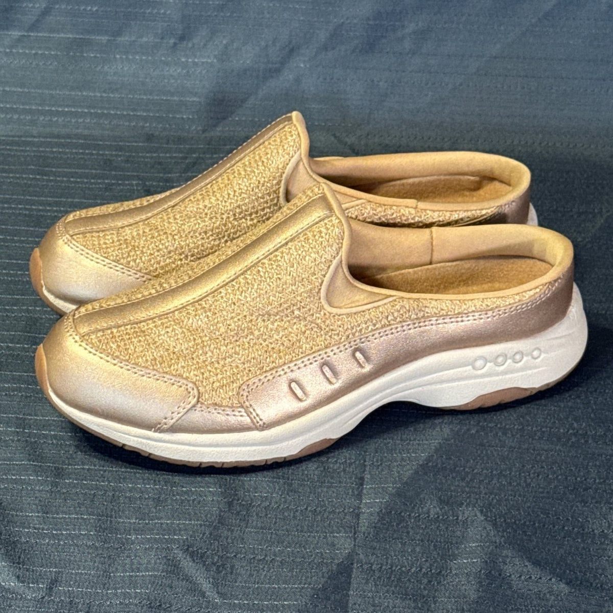 Angled view of rose-gold Easy Spirit slip-on sneakers with gold sparkle fabric and metallic trim.

