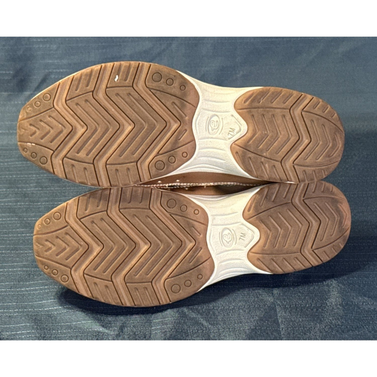 Soles of Easy Spirit mule sneakers showing brown tread, cream sections, and size 7M markings.
