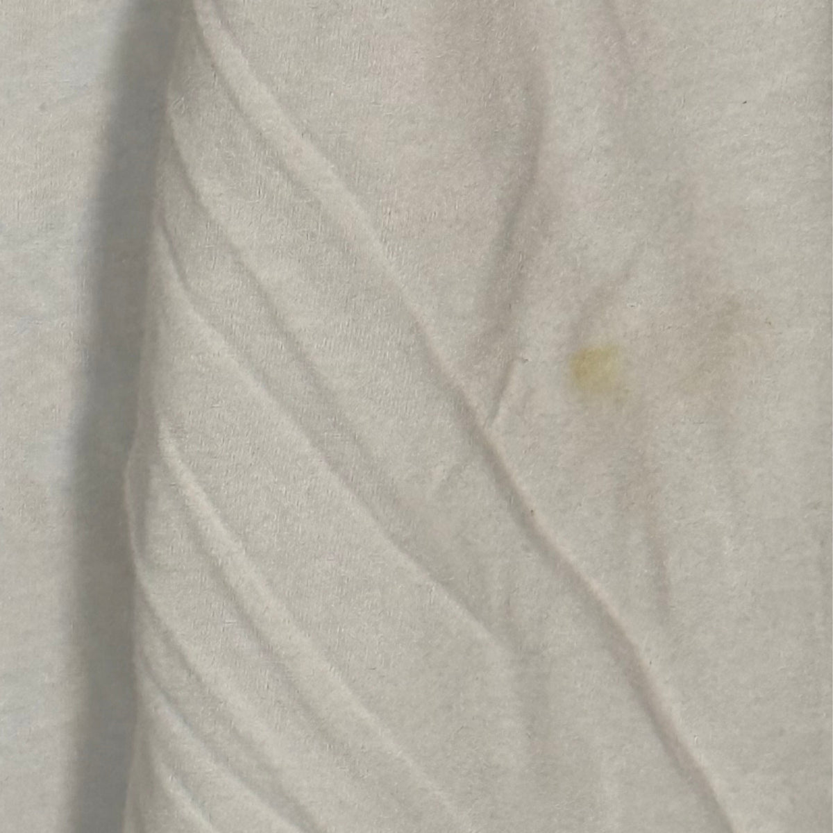 Close-up of small yellowish stain on white sleeve of Fanatics Washington Commanders hooded shirt.